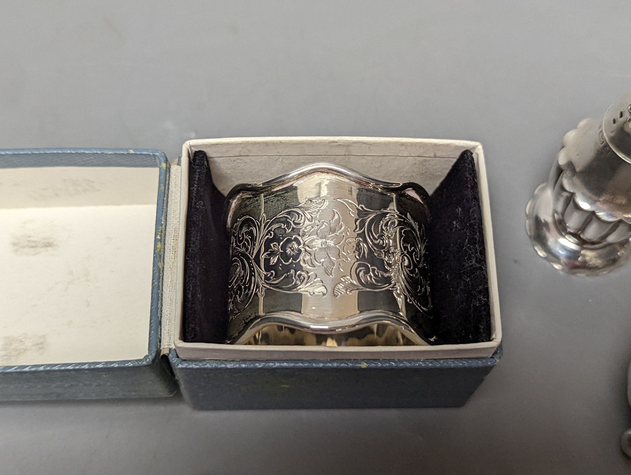 A cased silver napkin ring, seven assorted silver pepperettes including Guernsey can and a pair of plated sugar tongs.